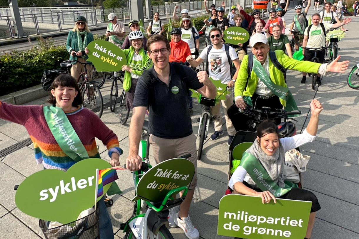 Foto av politikere fra MDG i en sykkelparade med grønne skilt.