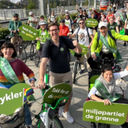 Foto av politikere fra MDG i en sykkelparade med grønne skilt.