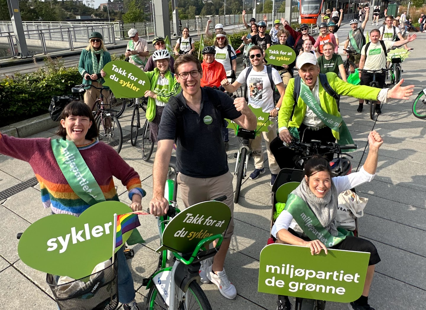 Foto av politikere fra MDG i en sykkelparade med grønne skilt.